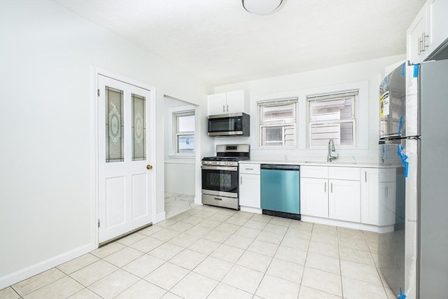 kitchen featuring white cabinets, stainless steel appliances, light countertops, and a sink