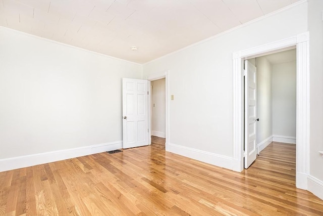 unfurnished room featuring visible vents, crown molding, light wood-type flooring, and baseboards