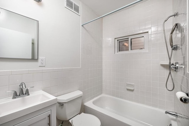 full bathroom featuring vanity, visible vents, bathing tub / shower combination, toilet, and tile walls