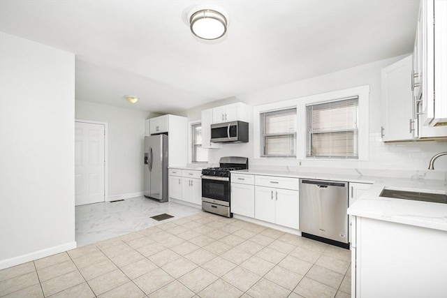 kitchen with visible vents, baseboards, white cabinets, stainless steel appliances, and a sink