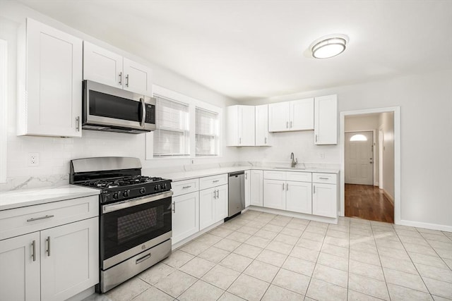 kitchen featuring a sink, white cabinets, backsplash, and stainless steel appliances