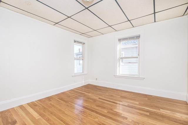 unfurnished room featuring a drop ceiling, light wood-type flooring, and baseboards