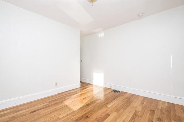 unfurnished room featuring visible vents, baseboards, and wood finished floors