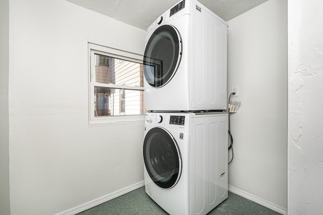 washroom with laundry area, baseboards, and stacked washer / drying machine