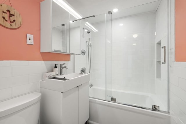 51 Warren St Unit 2-2, Waltham, MA 02453 - bathroom featuring tile walls, toilet, shower / bath combination with glass door, vanity, and a wainscoted wall