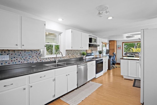 kitchen with range with gas stovetop, freestanding refrigerator, under cabinet range hood, a sink, and dishwasher