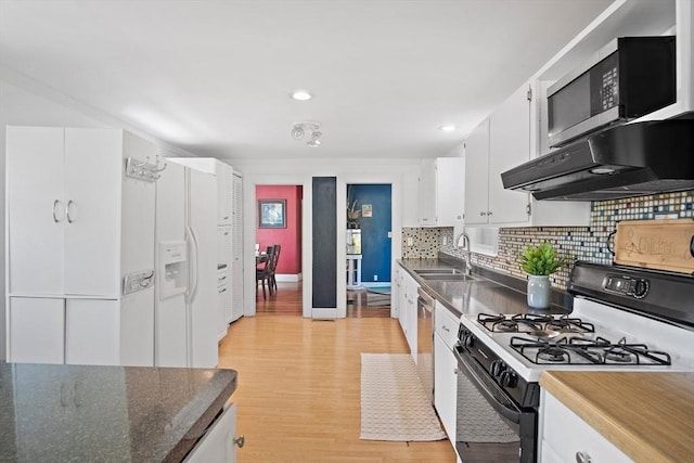 kitchen featuring decorative backsplash, a sink, under cabinet range hood, white cabinetry, and gas range oven