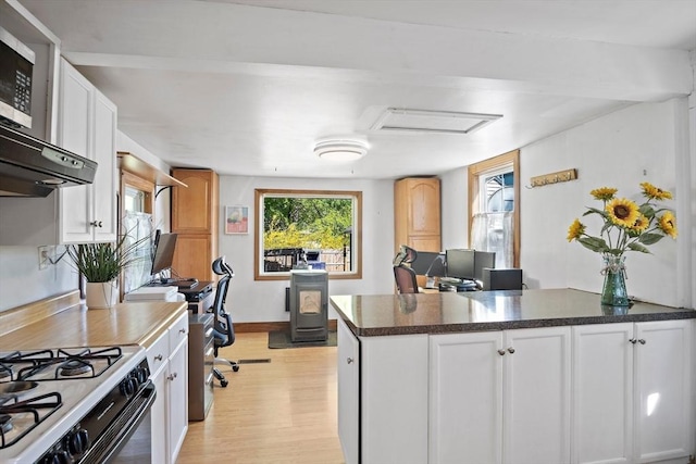 kitchen with dark countertops, baseboards, white cabinets, a peninsula, and light wood finished floors