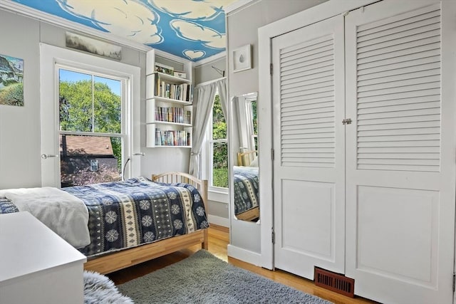 bedroom with visible vents, ornamental molding, and wood finished floors