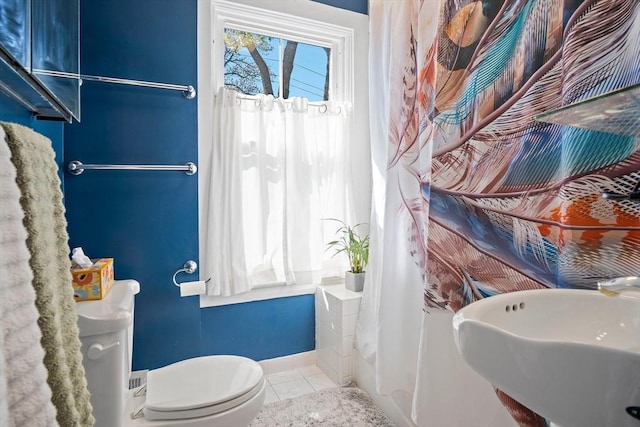 bathroom featuring a sink, baseboards, tile patterned flooring, and toilet