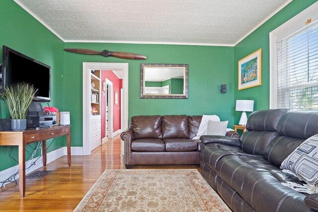 living area with baseboards, ornamental molding, plenty of natural light, and wood finished floors