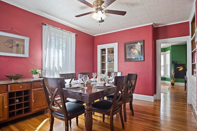 dining area featuring baseboards, ceiling fan, ornamental molding, and wood finished floors