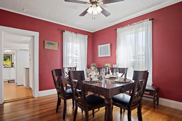 dining room featuring baseboards, ceiling fan, ornamental molding, and wood finished floors