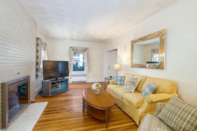 33 Samoset Ave, Quincy, MA 02169 - living room with radiator, wood finished floors, a fireplace, brick wall, and baseboards