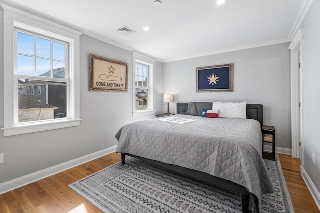 bedroom with visible vents, baseboards, wood finished floors, and ornamental molding