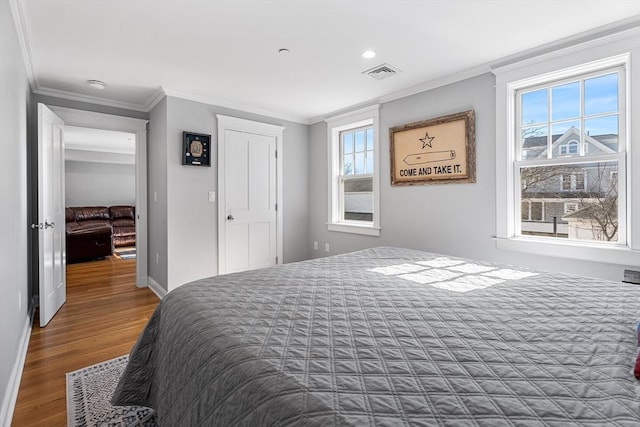 bedroom with visible vents, ornamental molding, baseboards, and wood finished floors