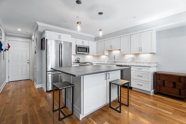 kitchen with a kitchen island, a breakfast bar area, appliances with stainless steel finishes, wood finished floors, and white cabinets