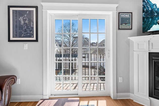 doorway featuring wood finished floors, a fireplace, and baseboards