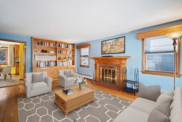 living room with baseboard heating, a fireplace, and hardwood / wood-style floors