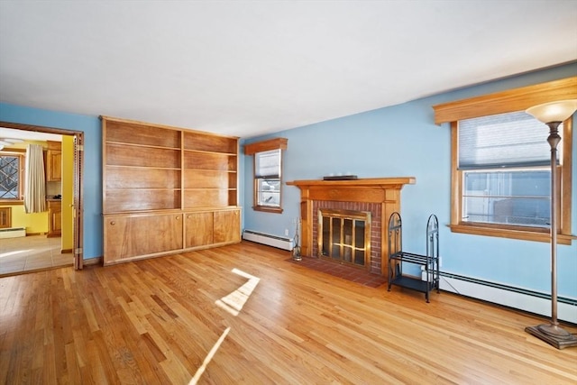 unfurnished living room featuring a brick fireplace, baseboard heating, and light hardwood / wood-style floors