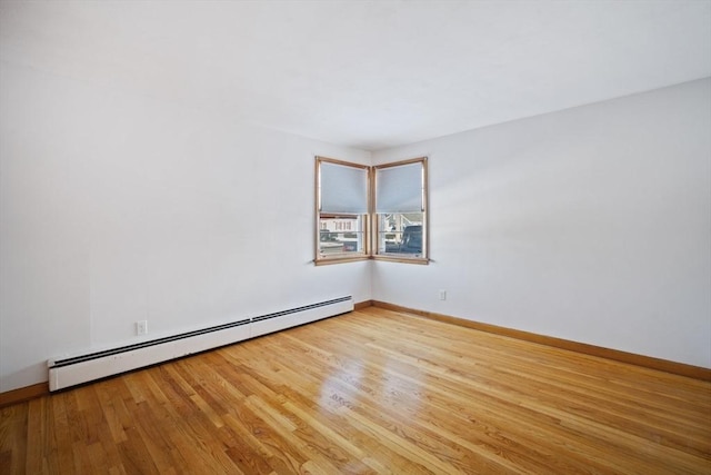 empty room with light hardwood / wood-style flooring and a baseboard heating unit