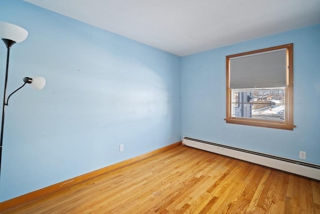 empty room with light wood-type flooring and a baseboard heating unit