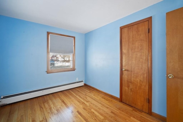 spare room featuring baseboard heating and light hardwood / wood-style floors