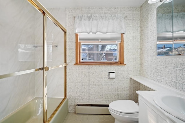 full bathroom featuring combined bath / shower with glass door, baseboard heating, tile walls, vanity, and toilet