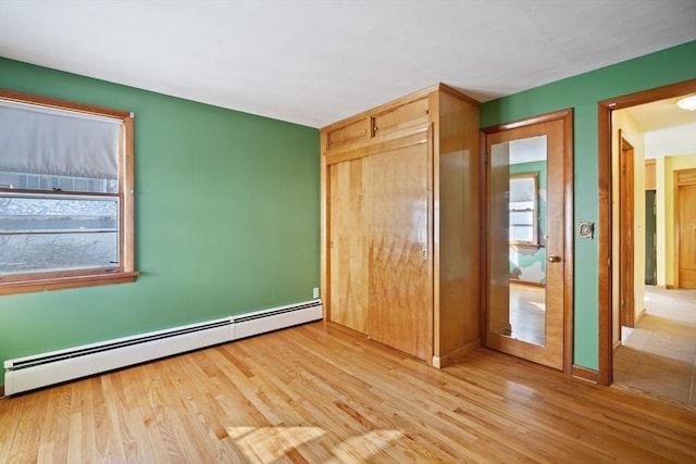 unfurnished bedroom featuring a baseboard heating unit and light hardwood / wood-style floors