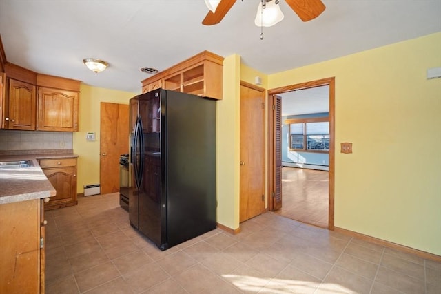 kitchen featuring tasteful backsplash, stainless steel gas range oven, black fridge, and baseboard heating