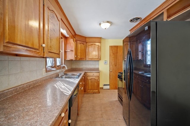 kitchen with sink, backsplash, a baseboard heating unit, light tile patterned floors, and black appliances