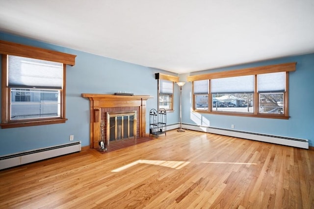 unfurnished living room with a baseboard radiator, a fireplace, and light wood-type flooring