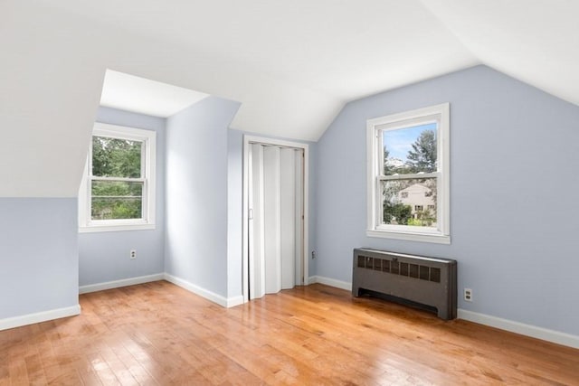 20 King St, Wilmington, MA 01887 - unfurnished bedroom with radiator heating unit, vaulted ceiling, light wood finished floors, and a closet