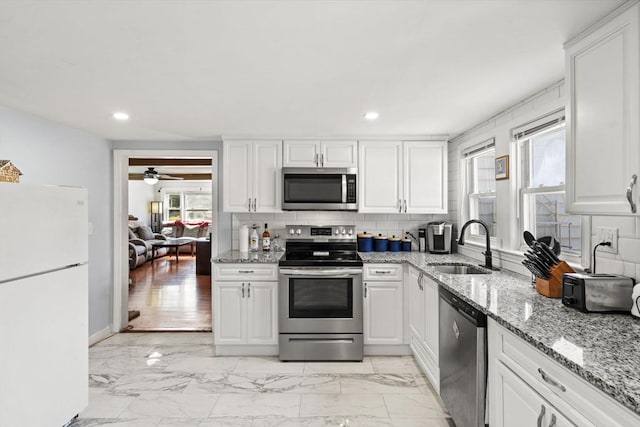 20 King St, Wilmington, MA 01887 - kitchen with appliances with stainless steel finishes, white cabinets, light marble finish floors, recessed lighting, and decorative backsplash