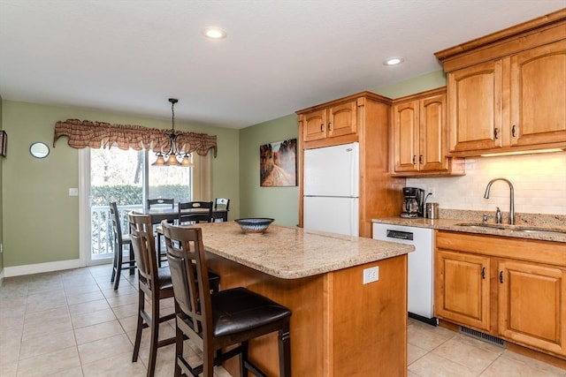 kitchen with sink, a center island, an inviting chandelier, decorative light fixtures, and white appliances