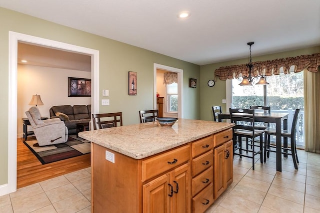 kitchen with light stone countertops, a center island, hanging light fixtures, a chandelier, and light tile patterned flooring