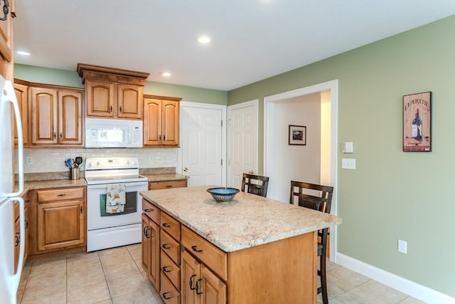 kitchen with a breakfast bar area, a kitchen island, light tile patterned flooring, and white appliances