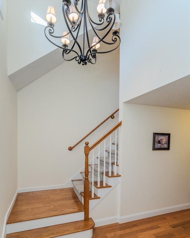 stairs featuring hardwood / wood-style floors, a chandelier, and a high ceiling