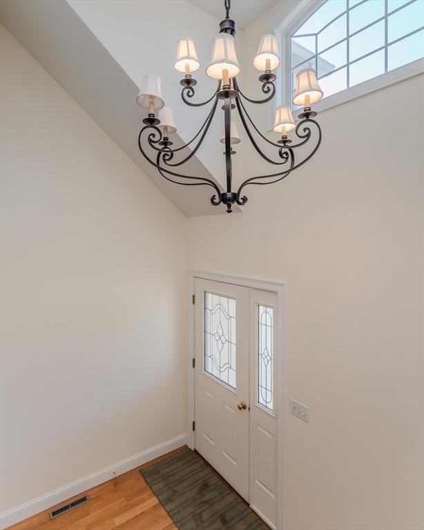 entryway featuring a chandelier, wood-type flooring, and a towering ceiling