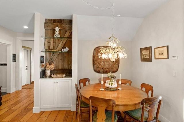 dining space featuring light hardwood / wood-style flooring, a notable chandelier, and vaulted ceiling