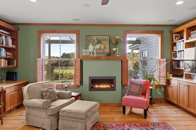 living area with crown molding and light wood-type flooring