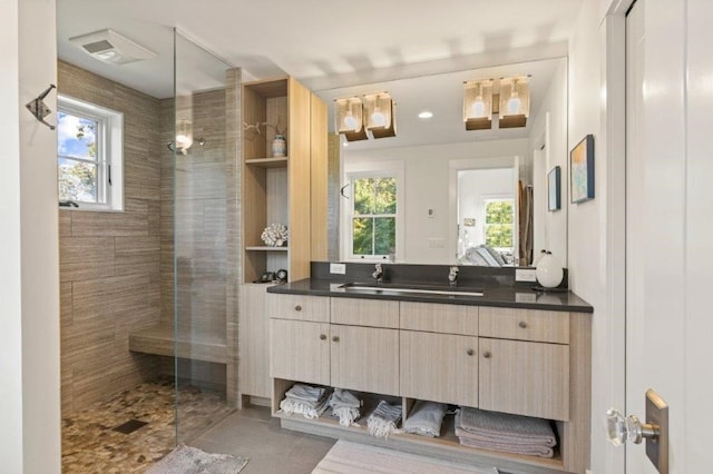 bathroom with vanity, tile patterned flooring, a tile shower, and a wealth of natural light