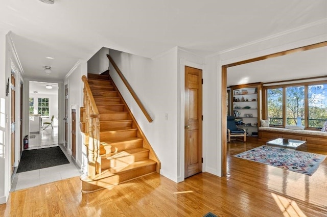 stairs with crown molding and hardwood / wood-style flooring