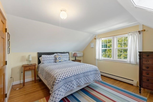 bedroom featuring light hardwood / wood-style flooring, vaulted ceiling, and a baseboard radiator