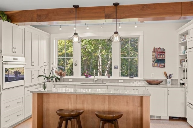 kitchen featuring white oven, white cabinetry, and light stone counters