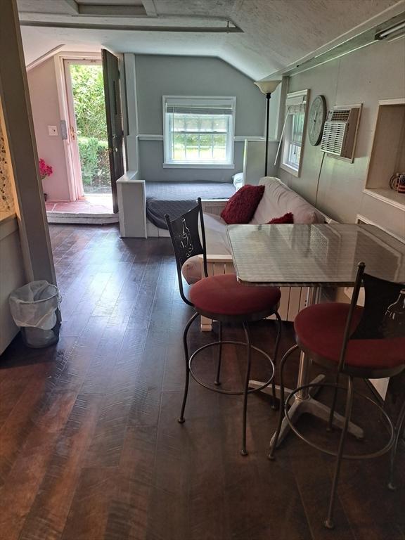 dining space featuring lofted ceiling, a wealth of natural light, a textured ceiling, and dark hardwood / wood-style flooring