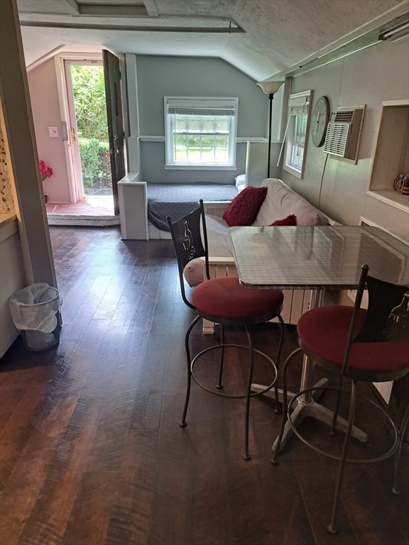 dining space with lofted ceiling, a healthy amount of sunlight, hardwood / wood-style floors, and a textured ceiling