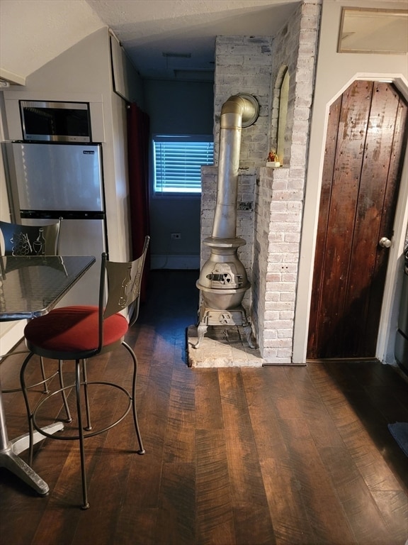 kitchen featuring dark wood-type flooring, vaulted ceiling, brick wall, and stainless steel appliances