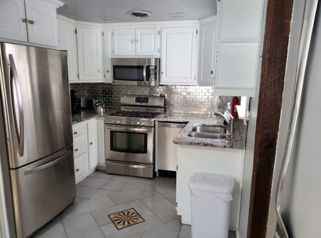 kitchen with light tile patterned floors, stainless steel appliances, stone countertops, decorative backsplash, and sink