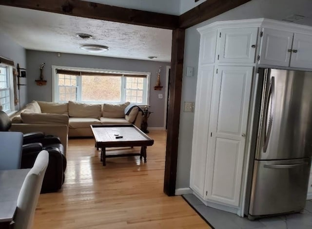 living room with beamed ceiling and light wood-type flooring